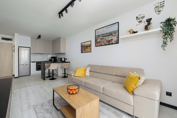 A cozy modern living room with a sofa, colorful wall art, and a wooden coffee table.