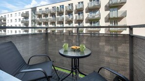 Un balcon avec une table, deux chaises et une vue sur un immeuble doté de balcons.