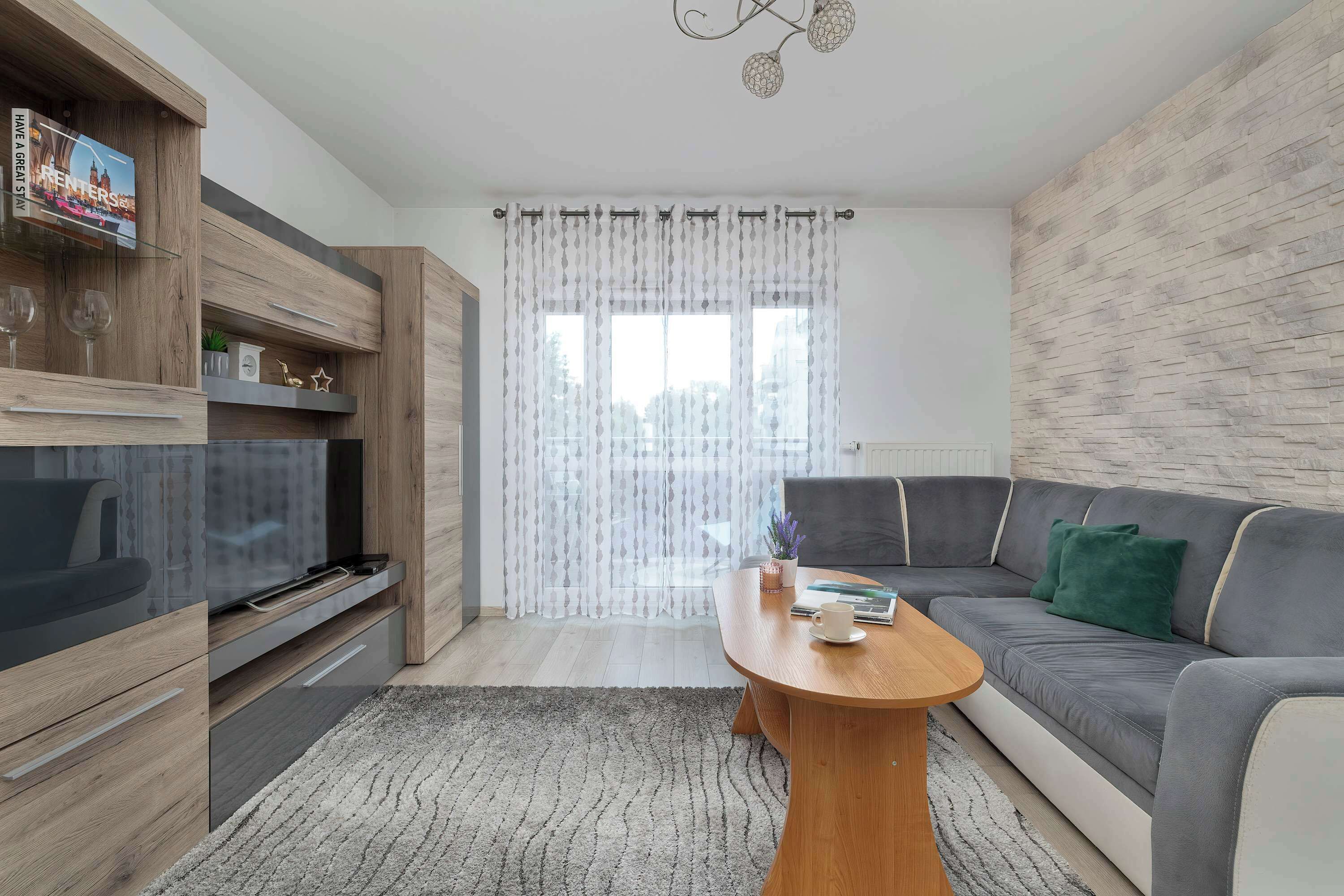 Un salon moderne avec un meuble TV en bois, un canapé gris et une table basse en bois.