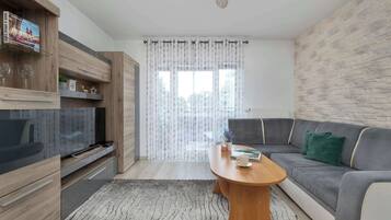 Un salon moderne avec un meuble TV en bois, un canapé gris et une table basse en bois.