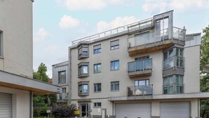 Ein modernes, mehrgeschossiges Gebäude mit Balkonen, großen Fenstern und einem überdachten Eingangsbereich.