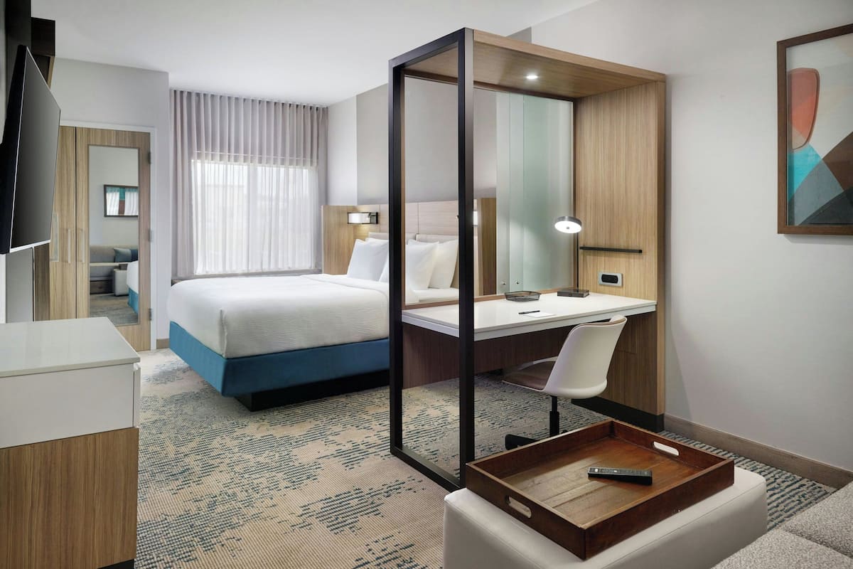 Una habitación de hotel con cama, escritorio, silla y televisor.