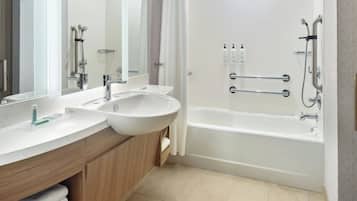 Ein modernes Badezimmer mit einem großen Waschbecken, einem Spiegel und einer Badewanne.