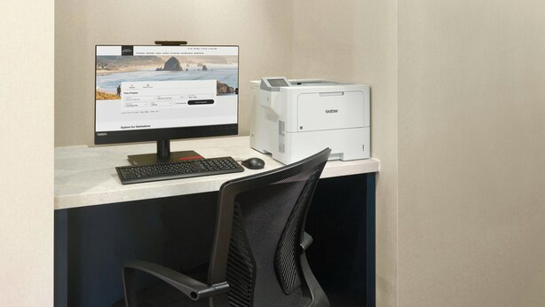 A computer desk with a monitor, keyboard, mouse, and a Brother printer. - Springhill Suites By Marriott Locust Grove (Locust Grove)