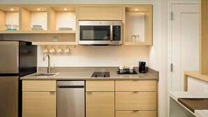 Une cuisine moderne dotée d’appareils électroménagers en acier inoxydable, de meubles de rangement en bois et d’un four à micro-ondes encastré.
