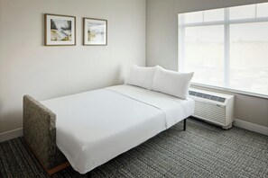 A single-bed room with a white bed, a window with a view, and two framed pictures on the wall. - Towneplace Suites By Marriott Perry Georgia National Fairgrounds (Perry)
