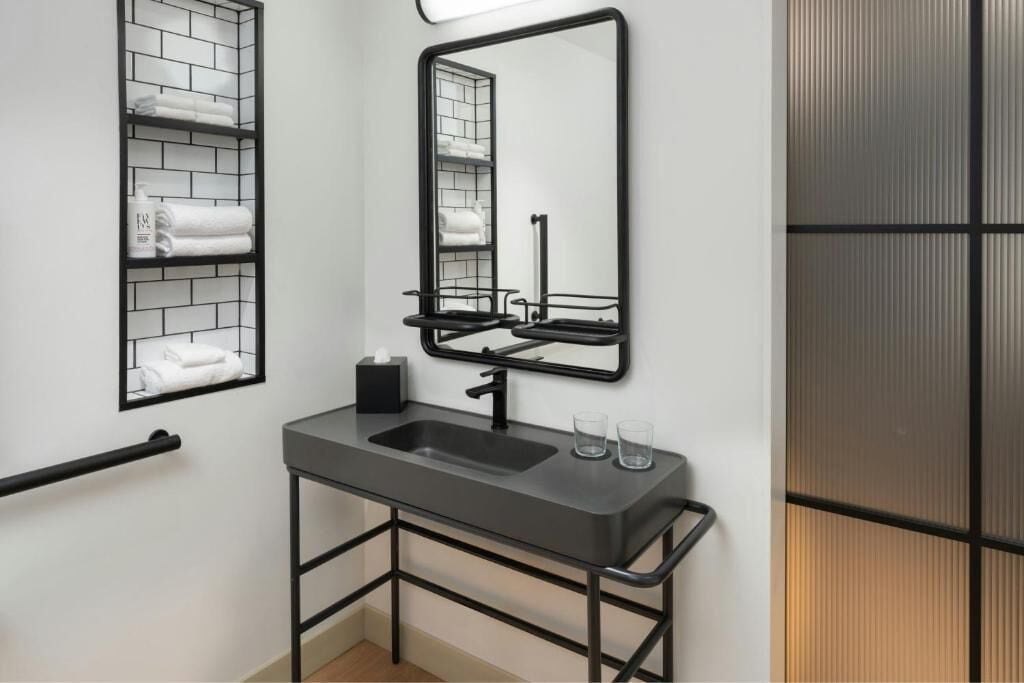 A modern bathroom with a black metal sink, a mirror, and a towel rack.