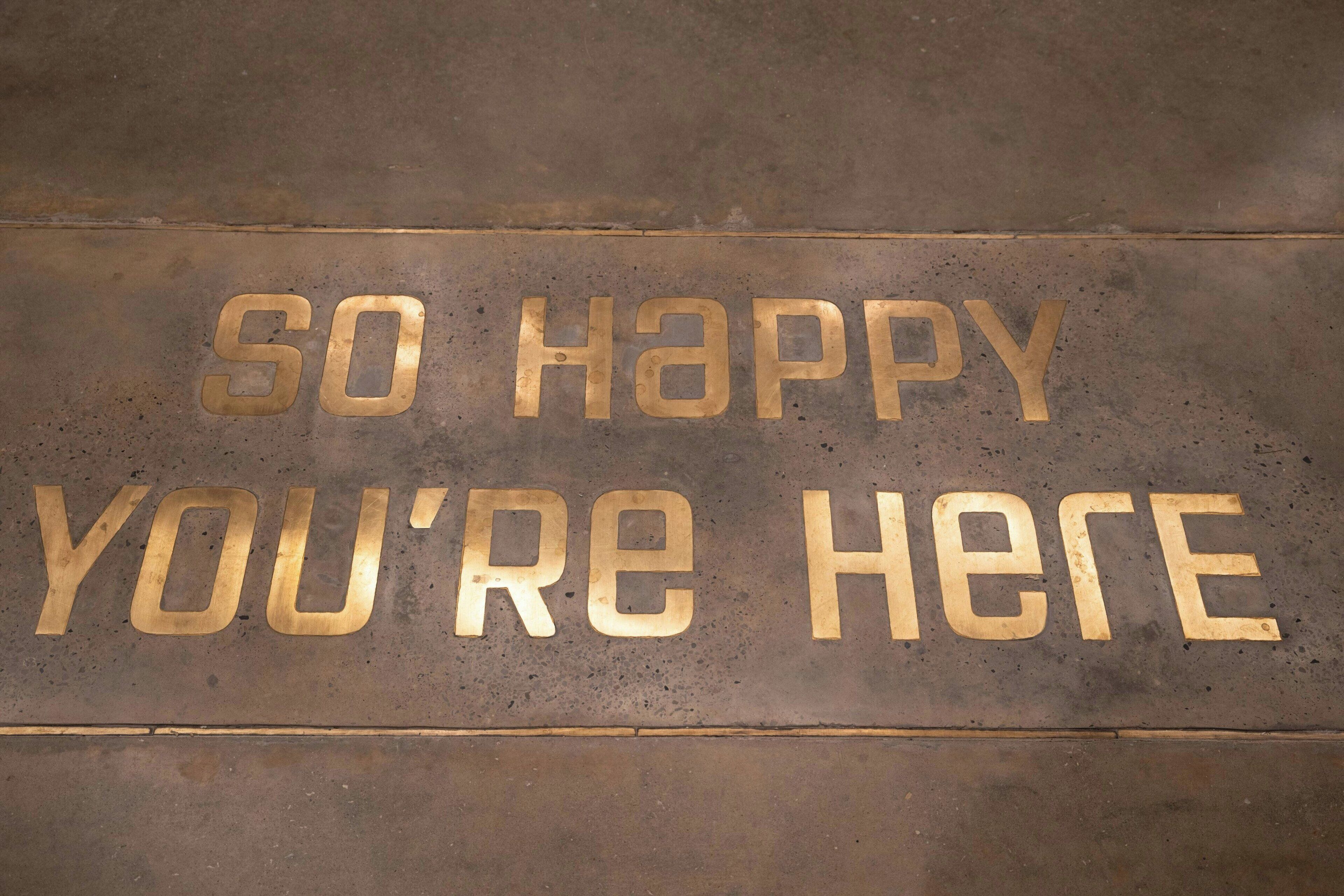 A floor with embossed text that reads "SO HAPPY YOU'RE HERE."