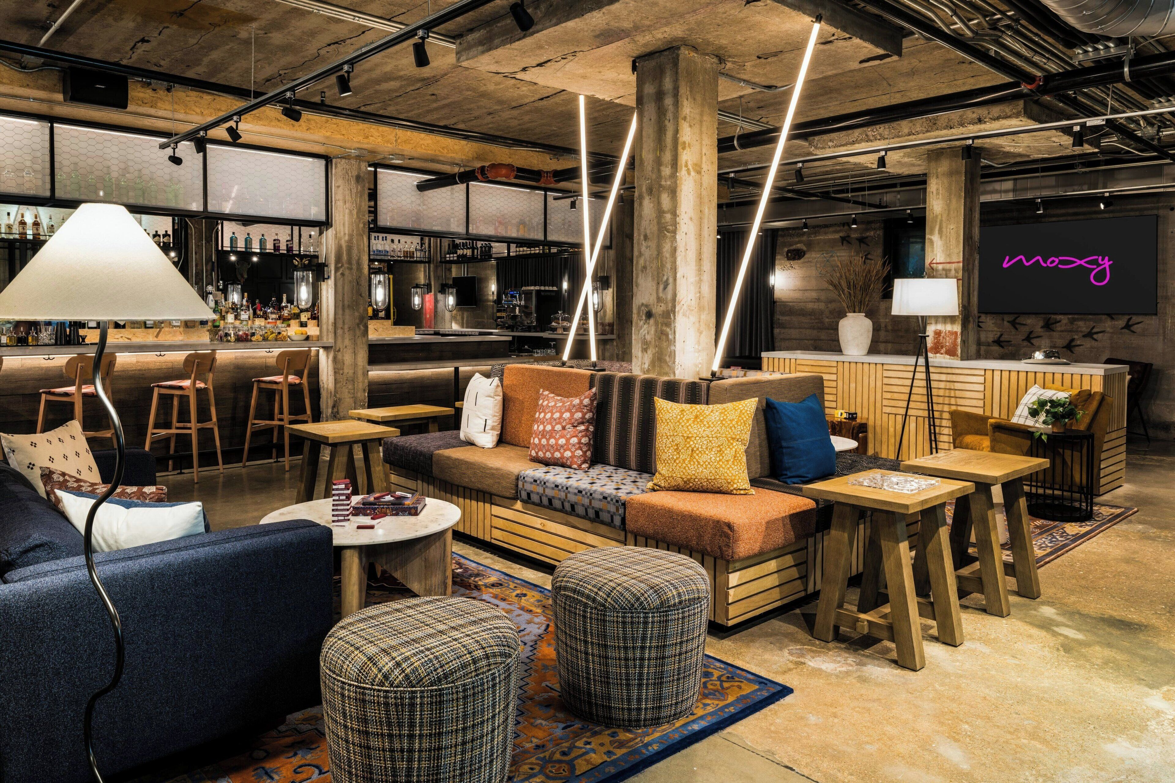 A modern lounge area with seating, a bar, and a neon sign.