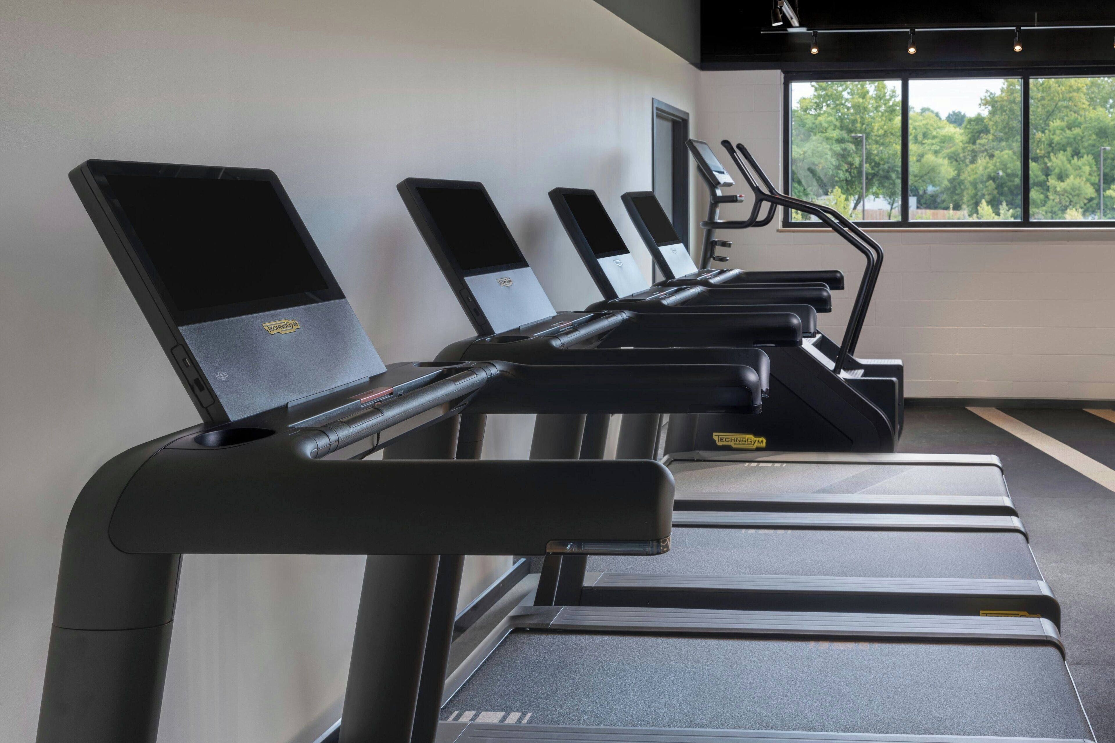 A row of stationary bikes in a gym with a window view.