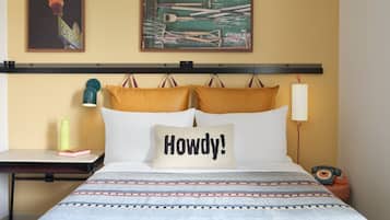 Une chambre d’hôtel comprenant un lit, une table de chevet, une lampe, un téléphone et une œuvre d’art murale.
