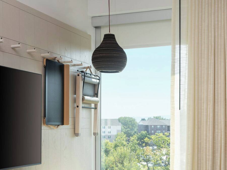 A modern room with a large window, a flat-screen TV, a small table, and a chair.