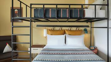 A bunk bed with a ladder, a bedside table, a lamp, and a telephone.