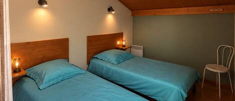 A bedroom with two beds, wooden ceiling, and a chair.