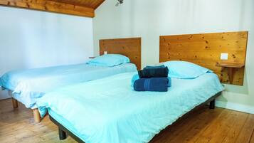 Une chambre avec deux lits en bois, chacun doté d’une tête de lit, et une petite table de chevet avec une lampe.