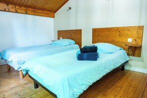 A room with two wooden beds, each with a headboard, and a small bedside table with a lamp.