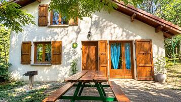 Un edificio rústico con fachada de madera, una mesa de picnic al frente y un camino de entrada de grava.
