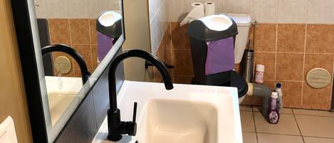 Un baño con un lavamanos blanco, un espejo y un inodoro.