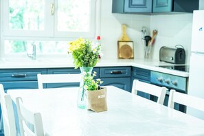A kitchen with white cabinets, a white table, and a vase with flowers. - Gîte Puma Sonnay, Isère (Sonnay)