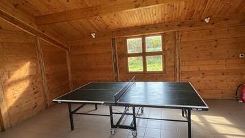 A ping pong table in a room with wooden walls and a tiled floor.