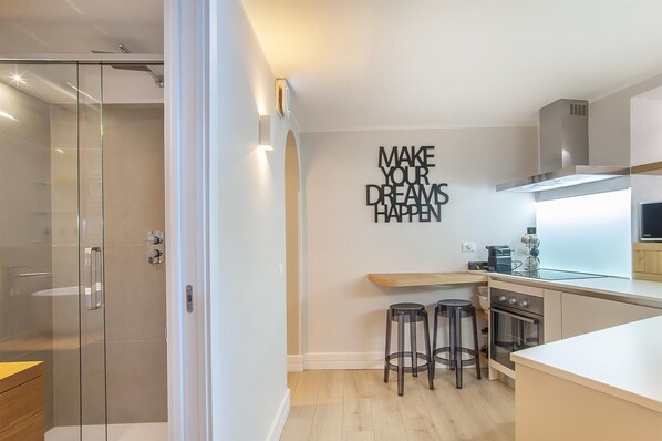 A modern kitchen with a glass shower enclosure, a motivational wall quote, and a breakfast bar. - Rental in Rome Ciambella Atmosphere Apartment (Rome)