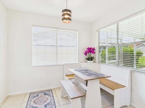 A dining area with a wooden bench and table, white walls, and a hanging light fixture. - Relaxing Rio Ranchero House with Golf Cart (Lady Lake)