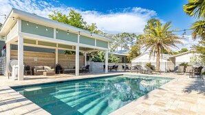 Une piscine dotée d’un patio couvert, de mobilier d’extérieur et de palmiers.
