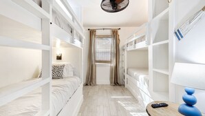 Une chambre d’hôtel compacte avec des lits superposés, une petite table avec une lampe et une fenêtre avec des rideaux.