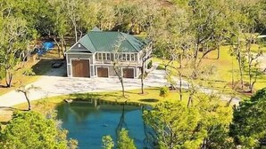Une maison dotée d’un toit végétalisé, entourée d’arbres et bordée d’un étang.