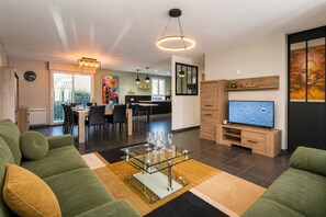 Ett modernt vardagsrum med en soffa, ett soffbord i glas, en tv och en matplats med stolar och ett bord.
