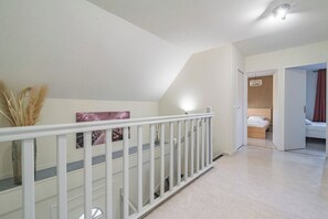 A staircase with a white railing leading to a bedroom with a bed and a nightstand. - Maison Harmonie by MM Suites (Cormontreuil)
