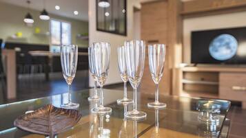 A glass table with five clear wine glasses and a decorative leaf placemat.