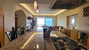 Una cocina moderna con una isla central, electrodomésticos de acero inoxidable e iluminación colgante.