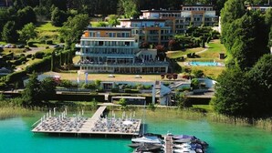 Ett hotell vid sjön med en brygga, båtar och ett poolområde.