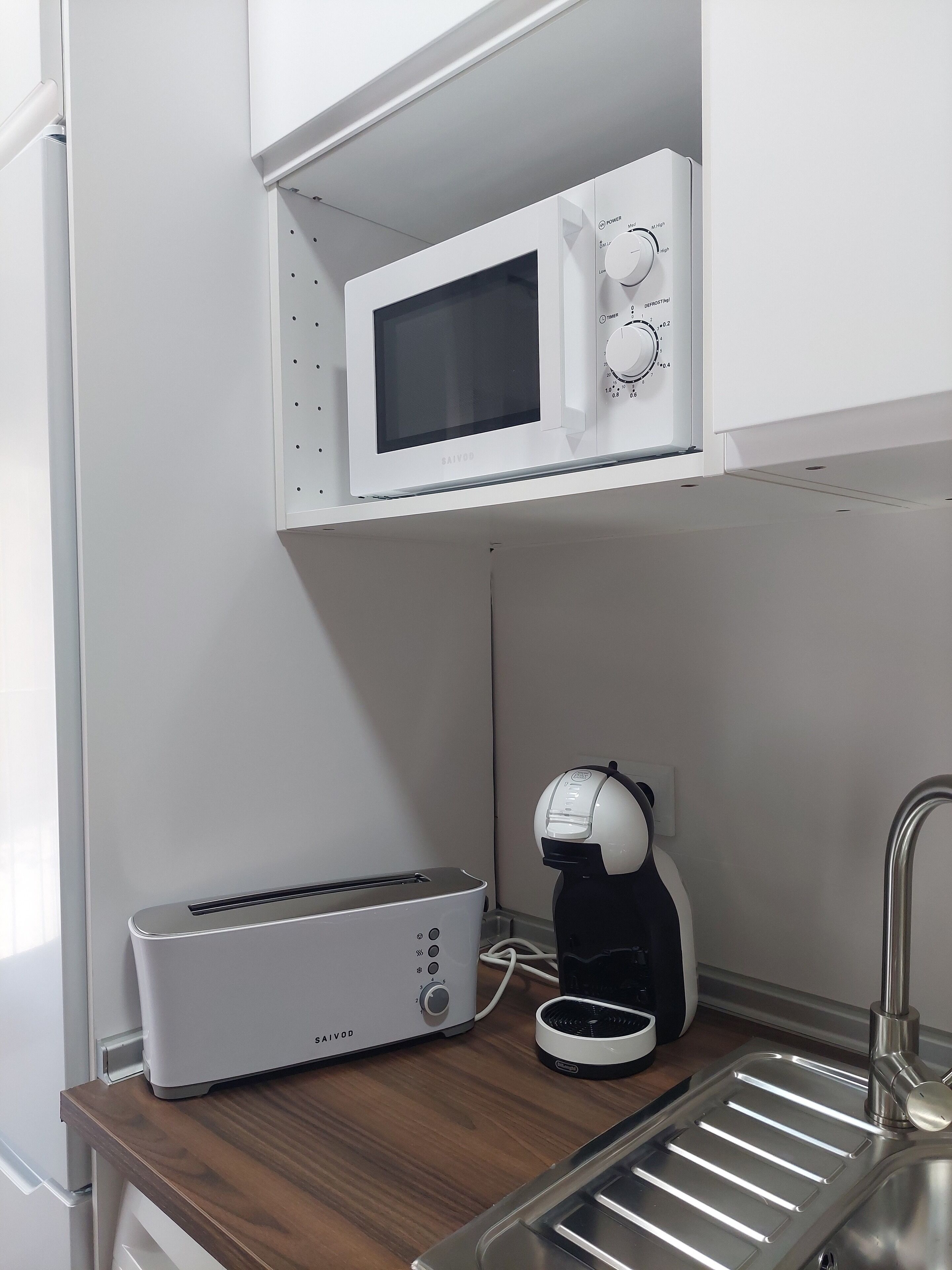 A kitchenette with a microwave, toaster, and coffee maker on a wooden countertop.