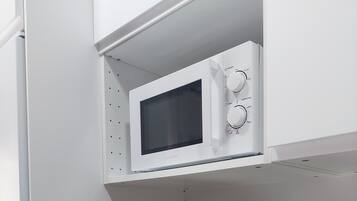A kitchenette with a microwave, toaster, and coffee maker on a wooden countertop.