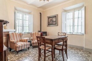 A room with a dining table, two striped armchairs, a wooden cabinet, and a framed picture on the wall. - Casa Elena - Villa Camelia (Ponte a Moriano (Lucca))