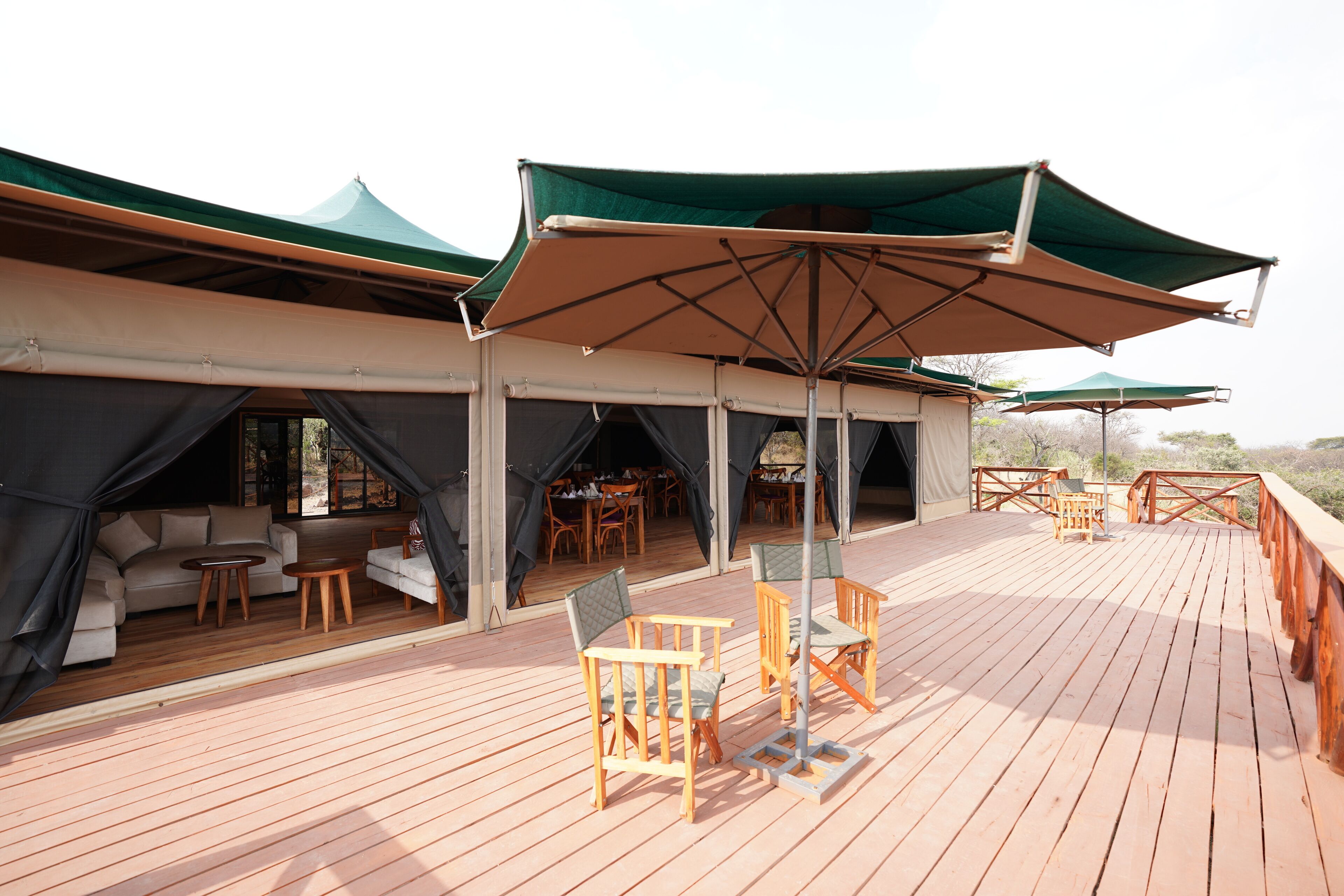 Eine Terrasse im Freien mit Holzmöbeln und grünen Markisen.
