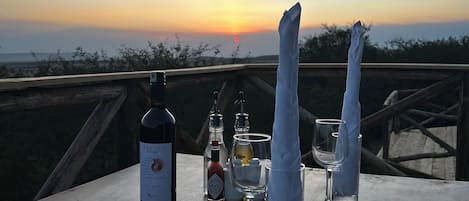 A table set for a meal with a bottle of wine, a bottle of sauce, salt and pepper shakers, and a glass of water.