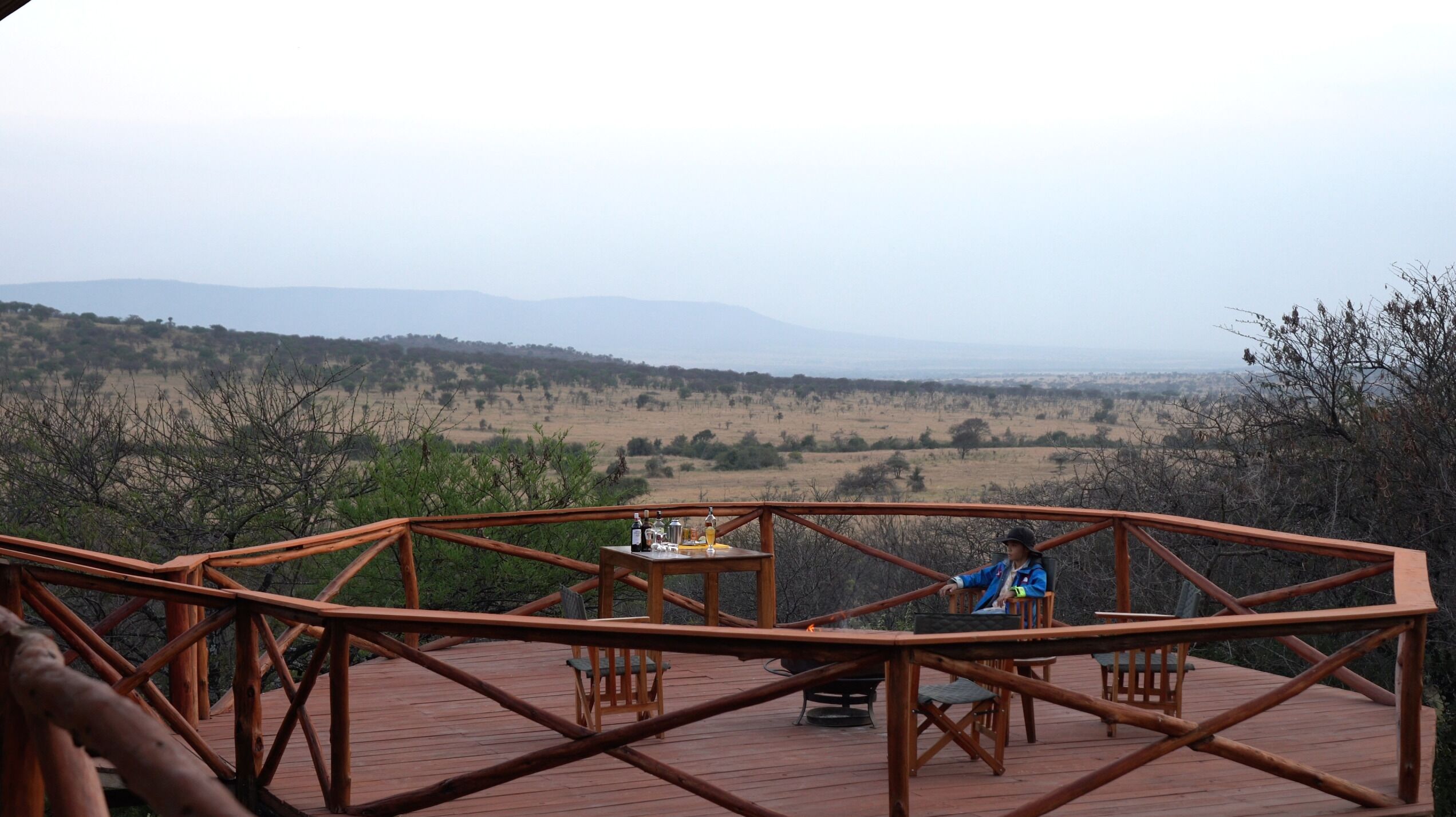 A wooden deck with a table and chairs overlooking a scenic landscape.