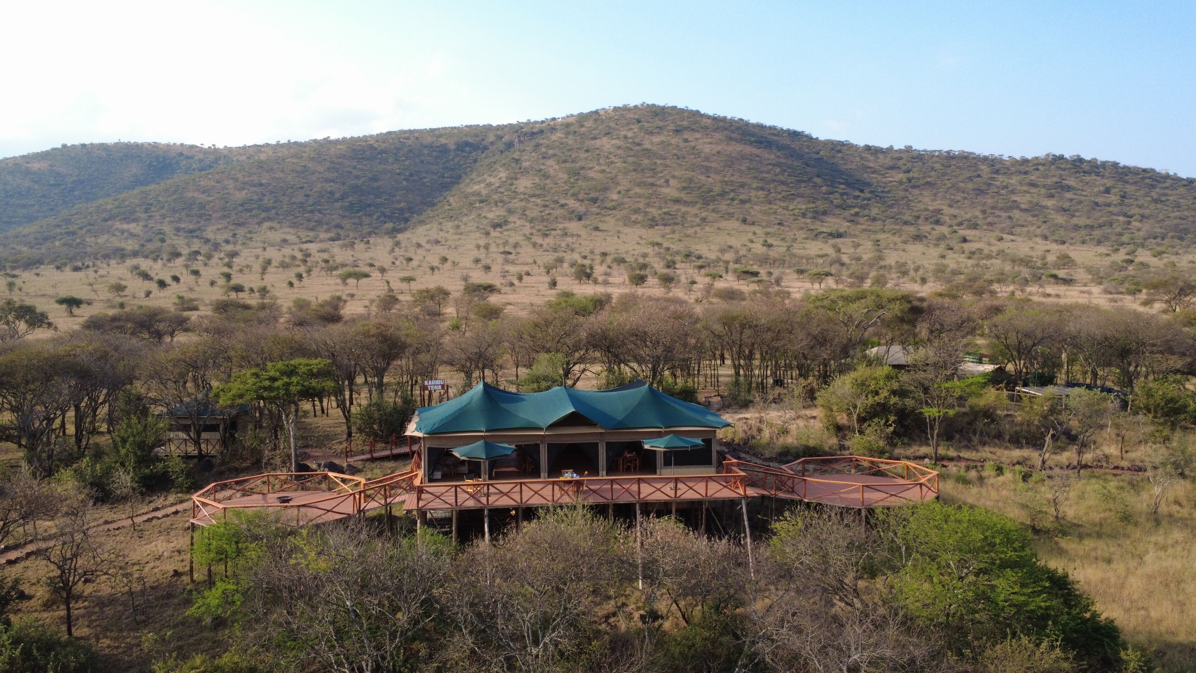 Un chalet doté d’un toit végétalisé et d’une terrasse en bois, niché au cœur d’un paysage montagneux.