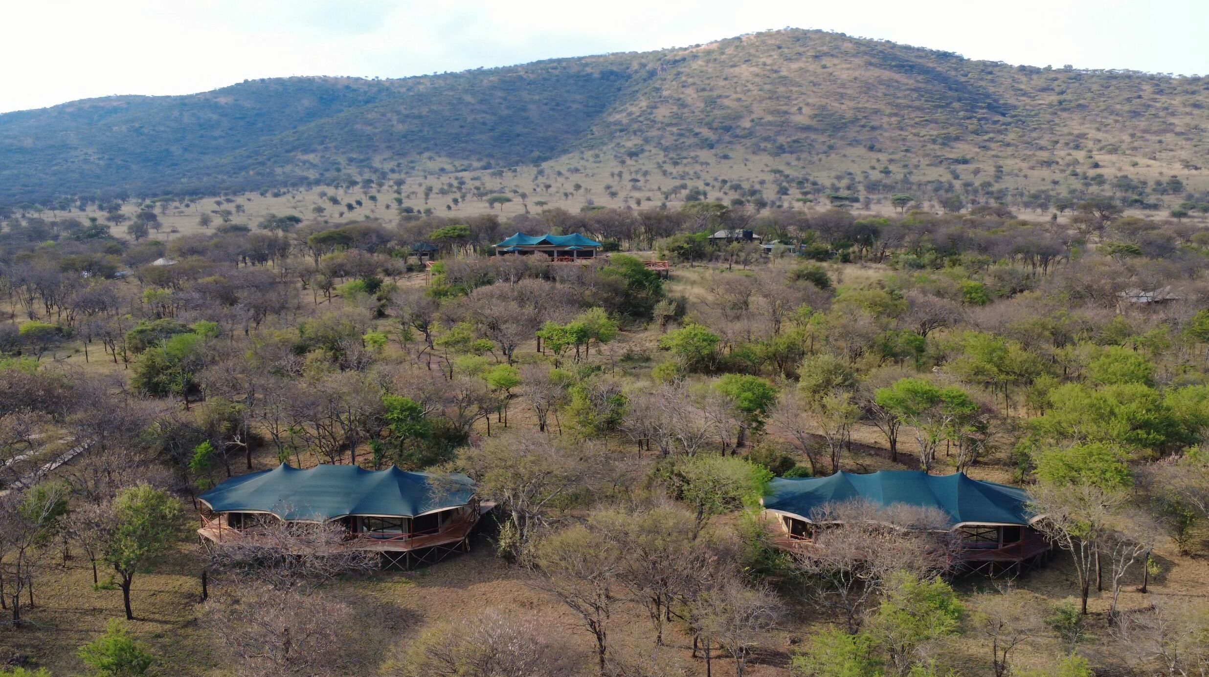 Un lodge de safari doté d’un grand espace ouvert et offrant une vue sur les collines environnantes.