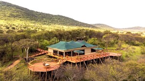 Un chalet doté d’un toit végétalisé, d’une terrasse en bois et offrant une vue sur un paysage vallonné.