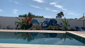 A swimming pool with a mural of a lighthouse and an octopus on the wall behind it. - Dar Asteroth, Villa for rent Djerba, Ghizen (Ghizen)