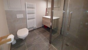 A bathroom with a toilet, a sink, and a glass shower enclosure.