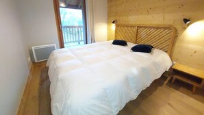 A bedroom with a large bed, wooden walls, a window, and a heater.