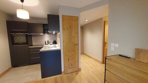 A modern kitchen with dark cabinets, a wooden door, and a wooden floor.