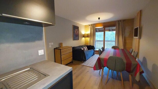 A compact kitchen with a modern stove and a dining area with a striped tablecloth.