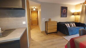 A compact living space with a kitchenette, a sofa, and a wooden cabinet.