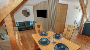 A dining area with a wooden table set for six, surrounded by chairs.